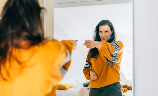 Femme qui se pointe du doigt dans un miroir